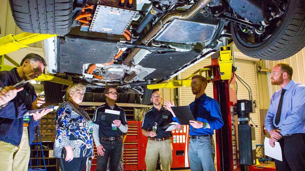 EcoCAR Challenge team viewing vehicle undercarriage as they help create an electric future.